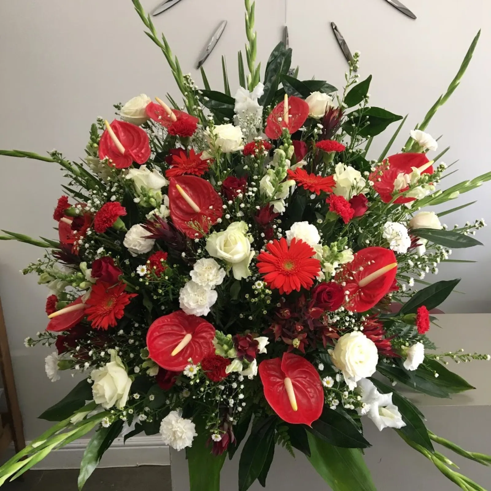 Large red and white arrangement of anthuriums, gerberas, white roses and carnations