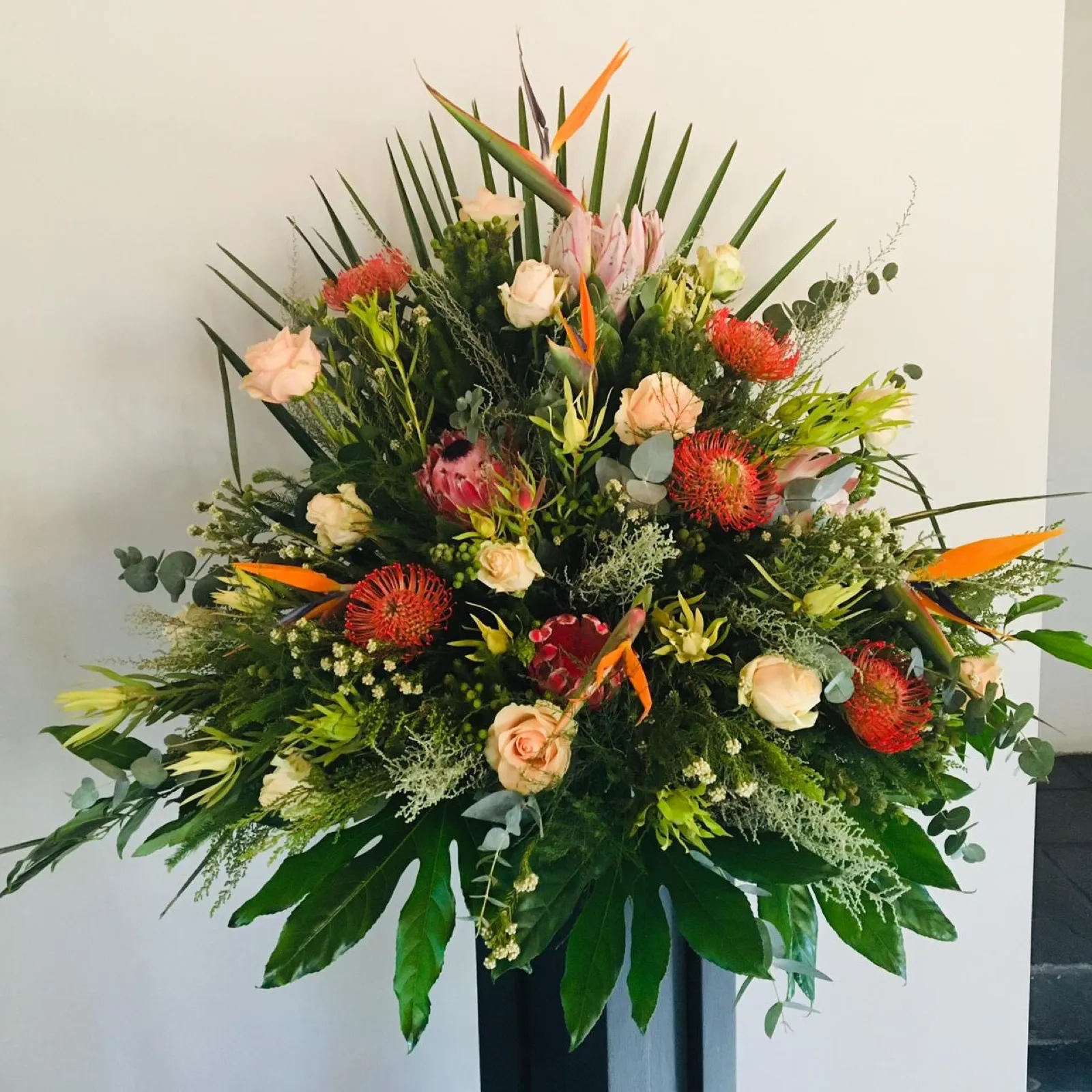Cape flower arrangement of pincushions, proteas, strelitzias and peach roses