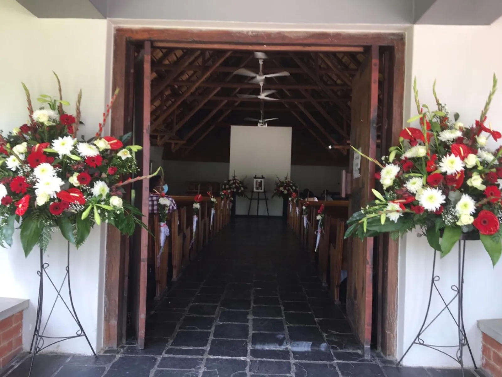 Two red and white standing sprays on wire stands flanking a chapel entrance