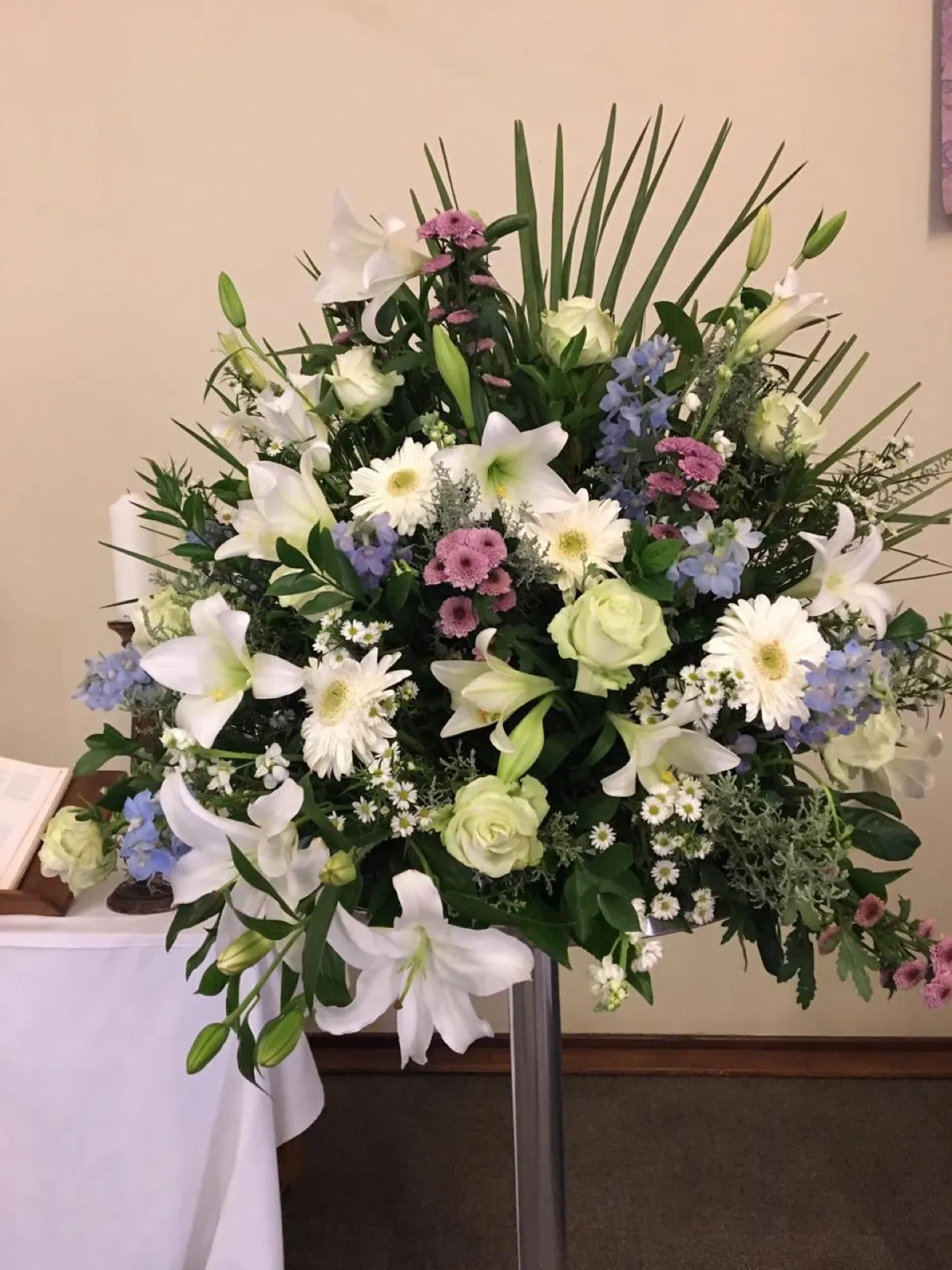 Church arrangement of white lilies, green roses, blue delphiniums and pink chrysanthemums