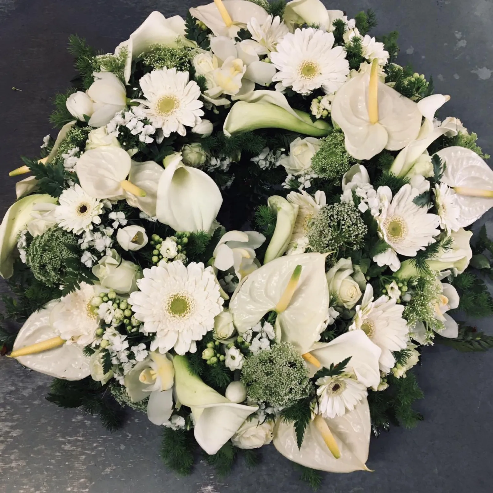 Round white wreath of anthuriums, calla lilies, gerberas and roses